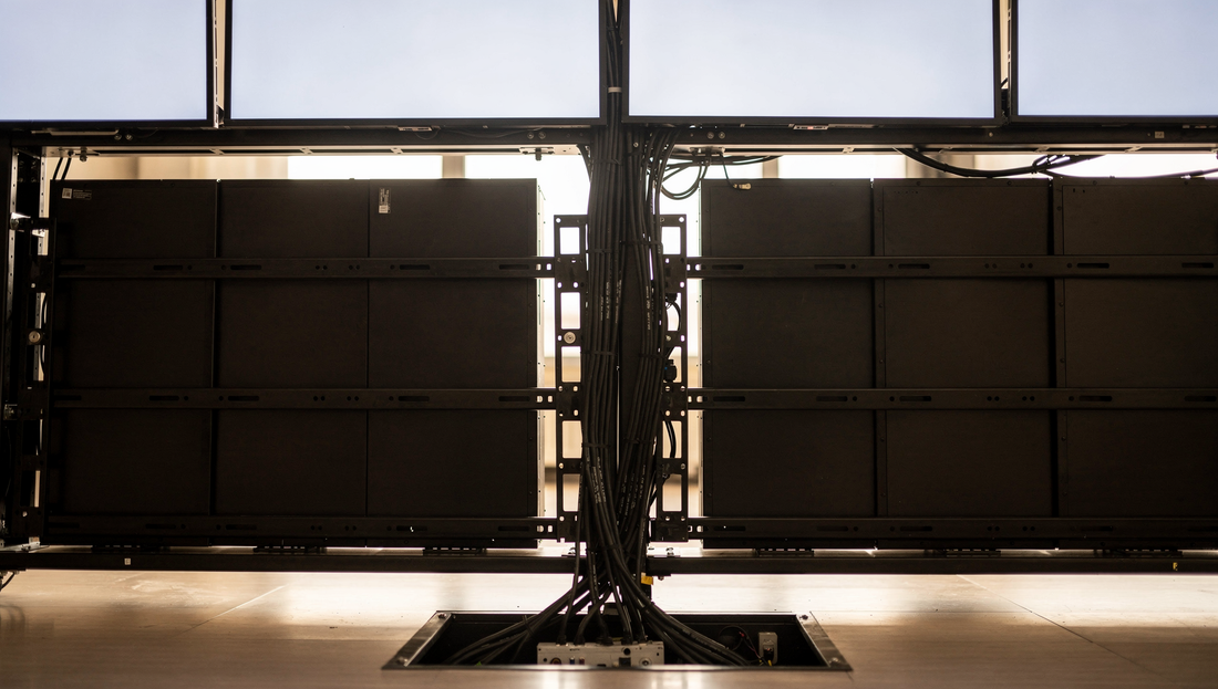 Video wall controller rack feeding a multi-panel display wall in a control room